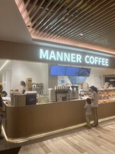 A takeaway Manner Coffee store in Shanghai with minimalist design and customers waiting in line.