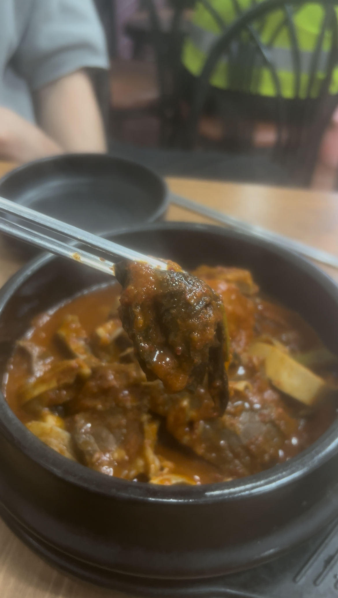 A piece of the tender beef lung held up by chopsticks.